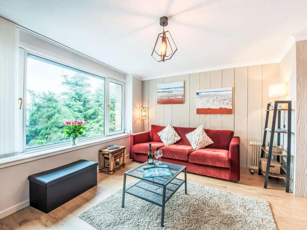 a living room with a red couch and a window at Holiday Home Highland View by Interhome in Drumnadrochit