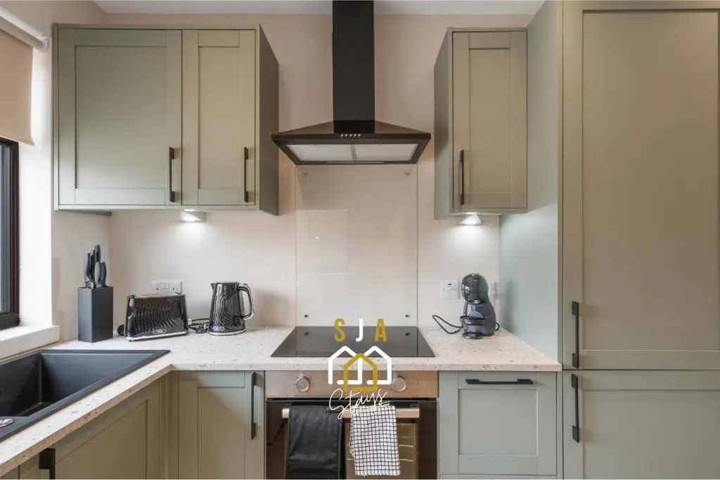 a kitchen with white cabinets and a stove top oven at Fraserburgh Residence - SJA Stays - Modern 3 Bed Apartment in Fraserburgh