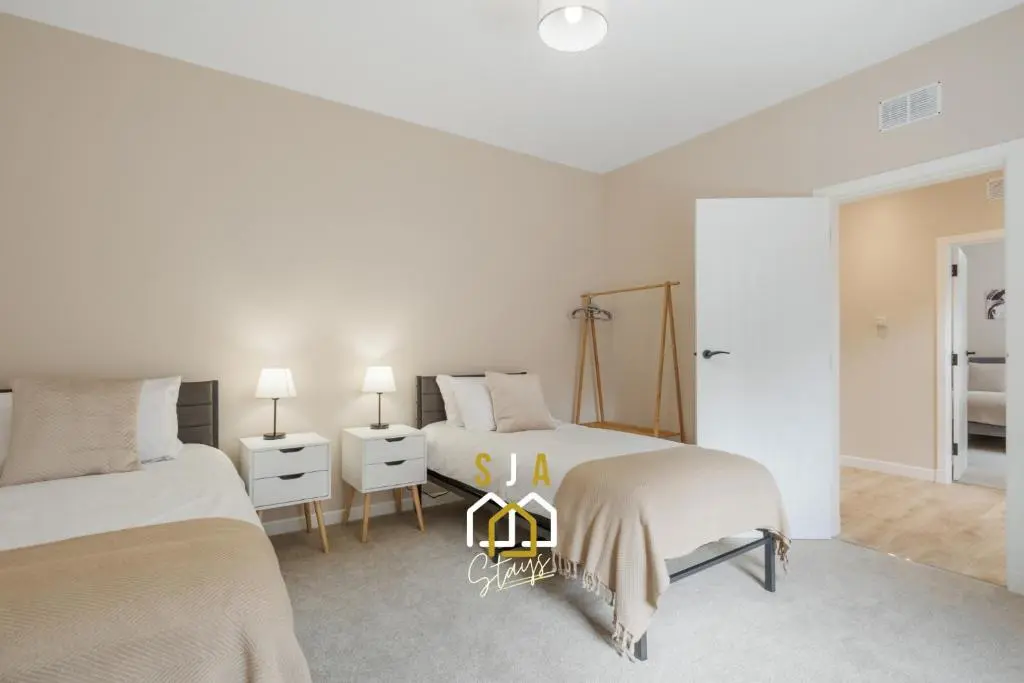 two beds in a room with white walls at Fraserburgh Residence - SJA Stays - Modern 3 Bed Apartment in Fraserburgh