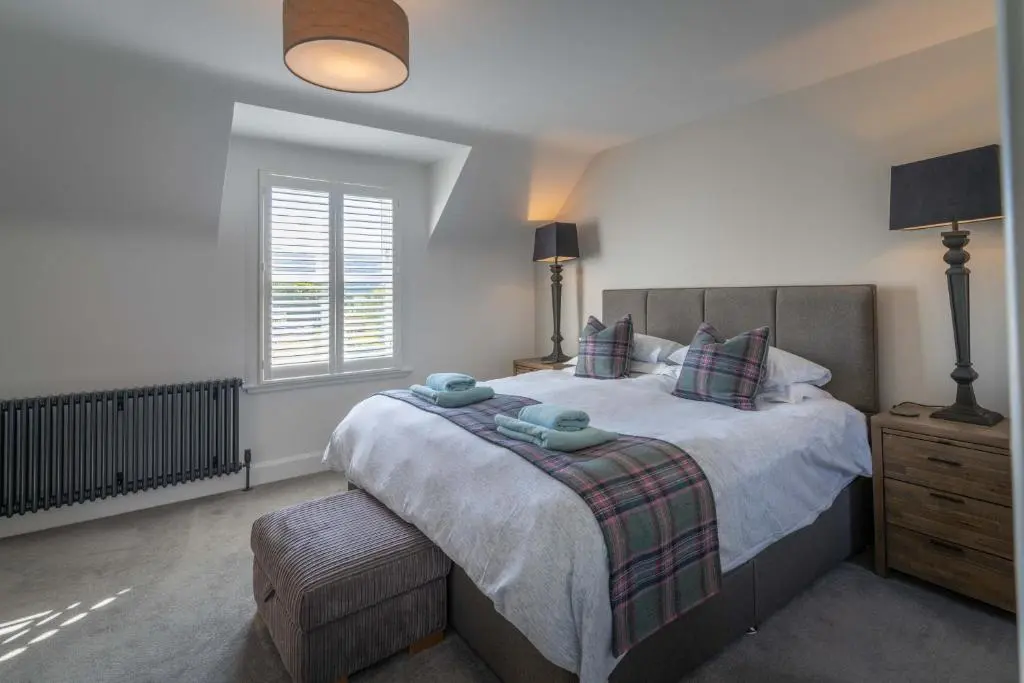 a bedroom with a large bed and a window at Glen Tilt House in Bridge of Tilt