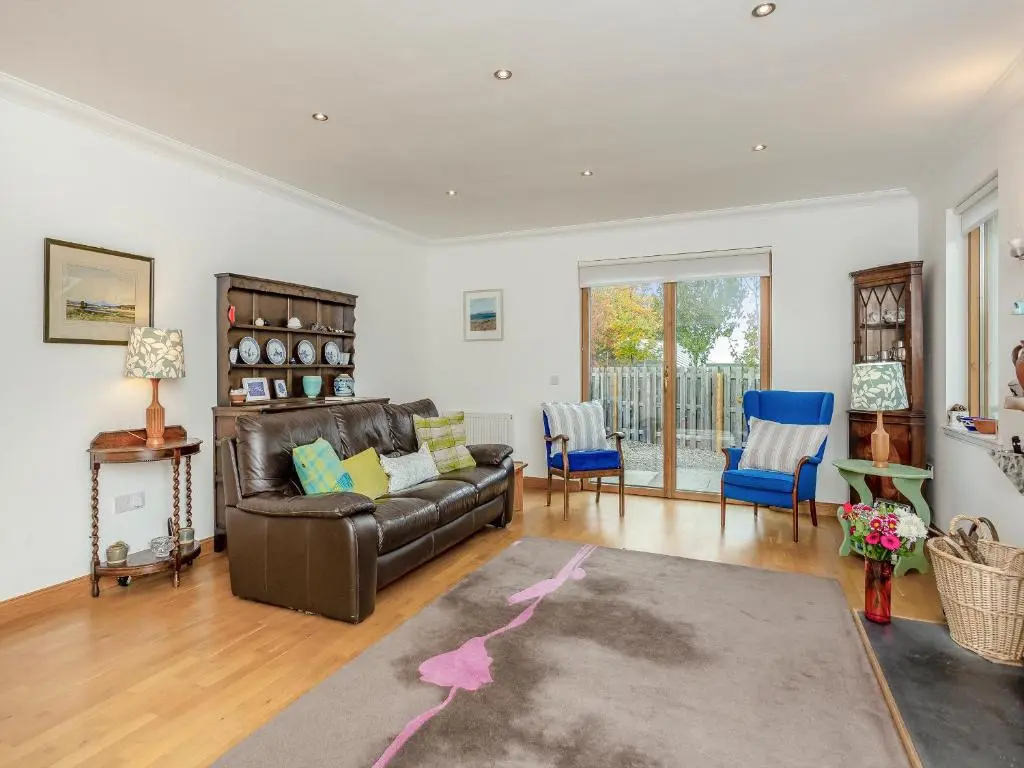 a living room with a leather couch and blue chairs at East Cottage in Cawdor