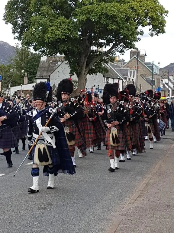 a group of people in uniforms marching in a parade at The Rowan in Boat of Garten
