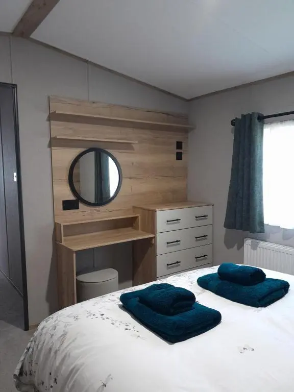 a bedroom with a bed with a vanity and a mirror at The Rowan in Boat of Garten