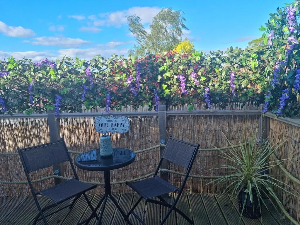 a table and two chairs and a fence with flowers at Village view apartment in Auldearn