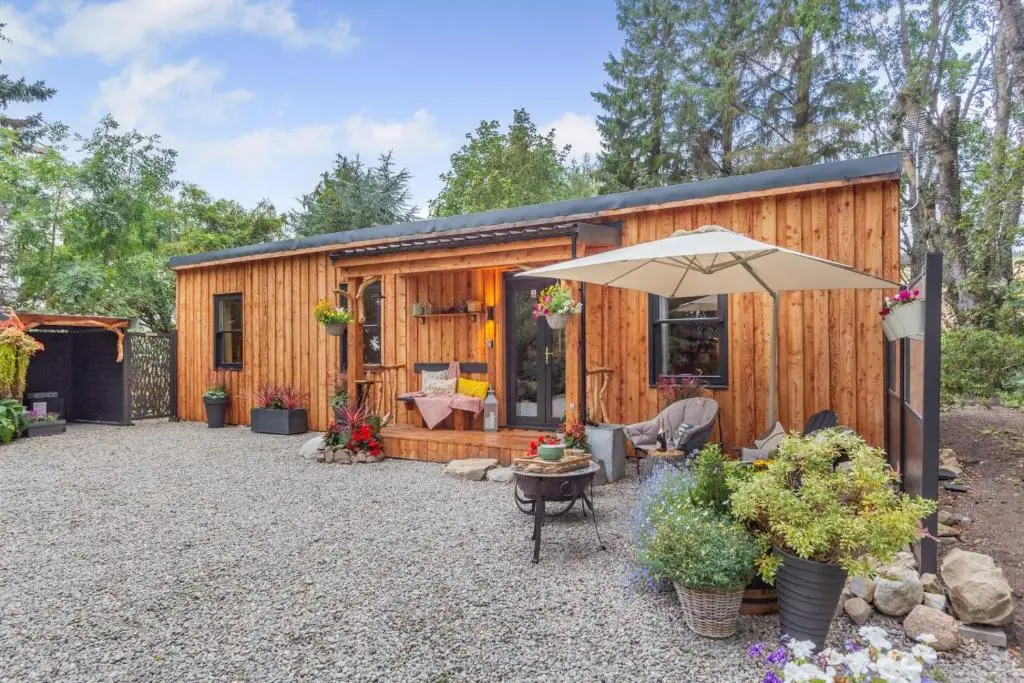 a cabin with an umbrella and a patio at 2 Bed in Invergordon oc-c33073 in Invergordon