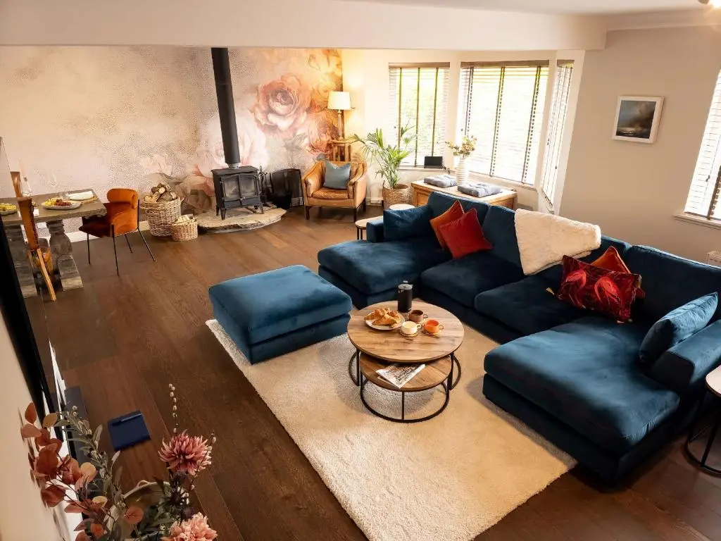 a living room with a blue couch and a table at 18 Dalfaber Park- with hot tub in Aviemore in Aviemore