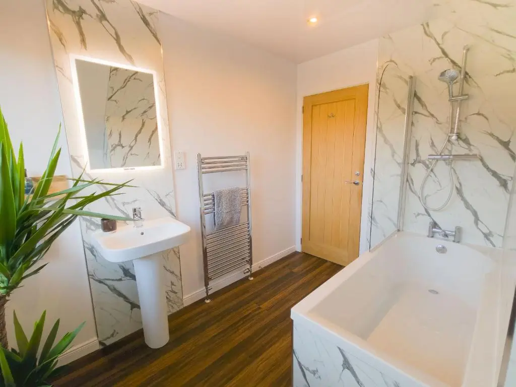 a bathroom with a sink and a tub and a mirror at 18 Dalfaber Park- with hot tub in Aviemore in Aviemore