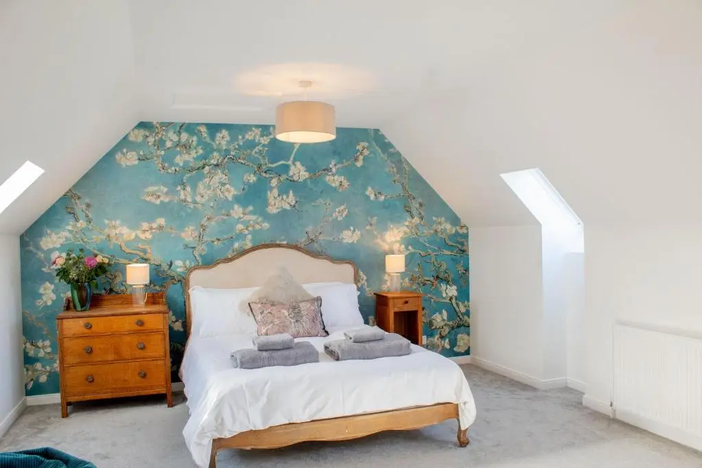 a bedroom with a bed with a floral wallpaper at 18 Dalfaber Park- with hot tub in Aviemore in Aviemore