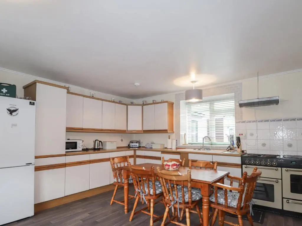 a kitchen with a table and chairs and a refrigerator at Ivy House in Kingussie