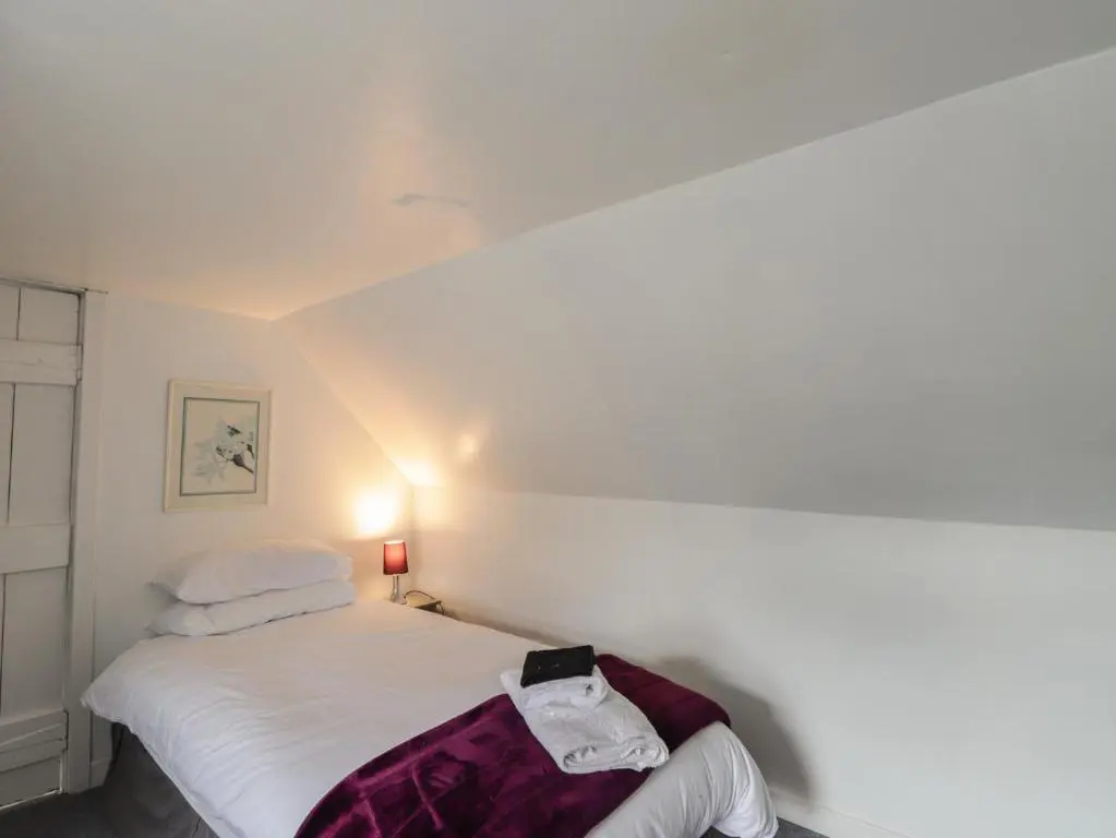 a bedroom with a white bed with a bag on it at Ivy House in Kingussie