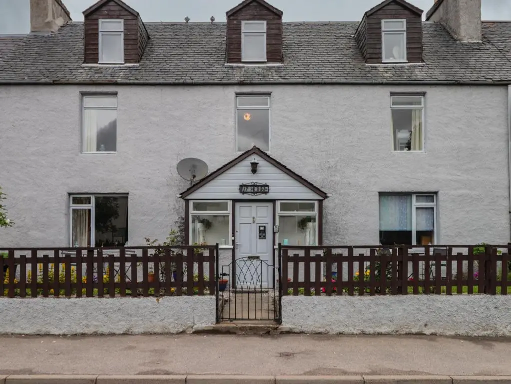 a white house with a wooden fence in front of it at Ivy House in Kingussie