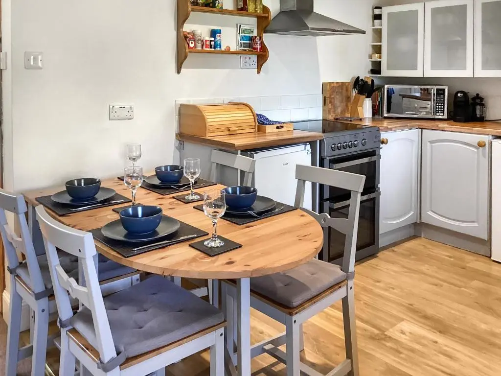 a kitchen with a wooden table with wine glasses on it at Old Laurel Cottage in Jemimaville