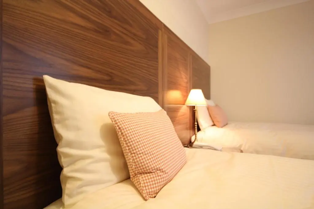 a hotel room with a bed with a wooden headboard at Strathburn Hotel Inverurie by Compass Hospitality in Inverurie