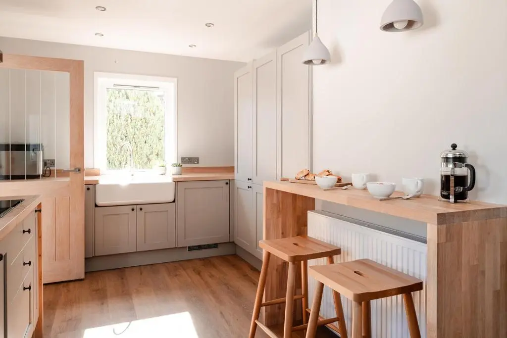 a kitchen with white cabinets and a counter with stools at Kintail - Seasgair Lodges in Inverdruie