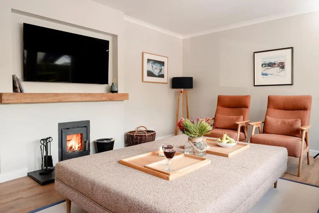 a living room with a table and a fireplace at Kintail - Seasgair Lodges in Inverdruie