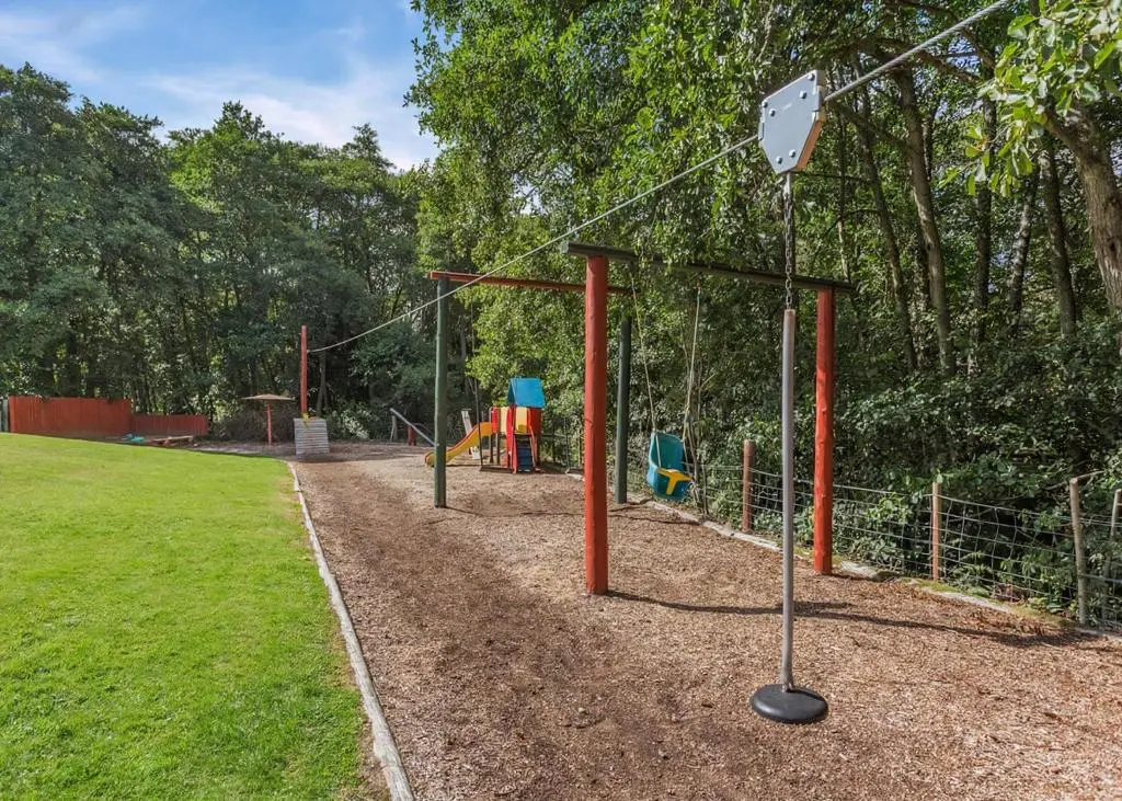 a playground in a park with a sign on a pole at Delny Highland Lodges in Barbaraville