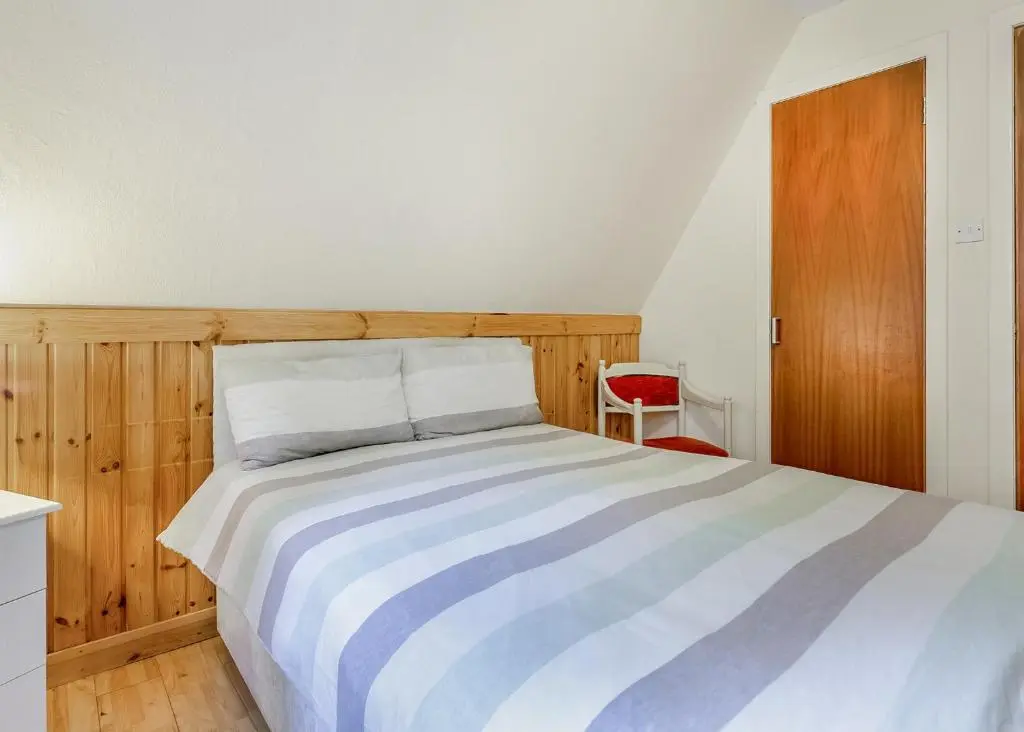 a bedroom with a bed and a red chair at Delny Highland Lodges in Barbaraville