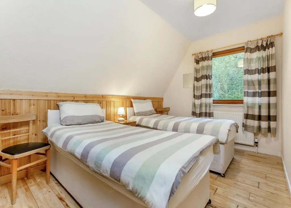 two beds in a room with a window at Delny Highland Lodges in Barbaraville