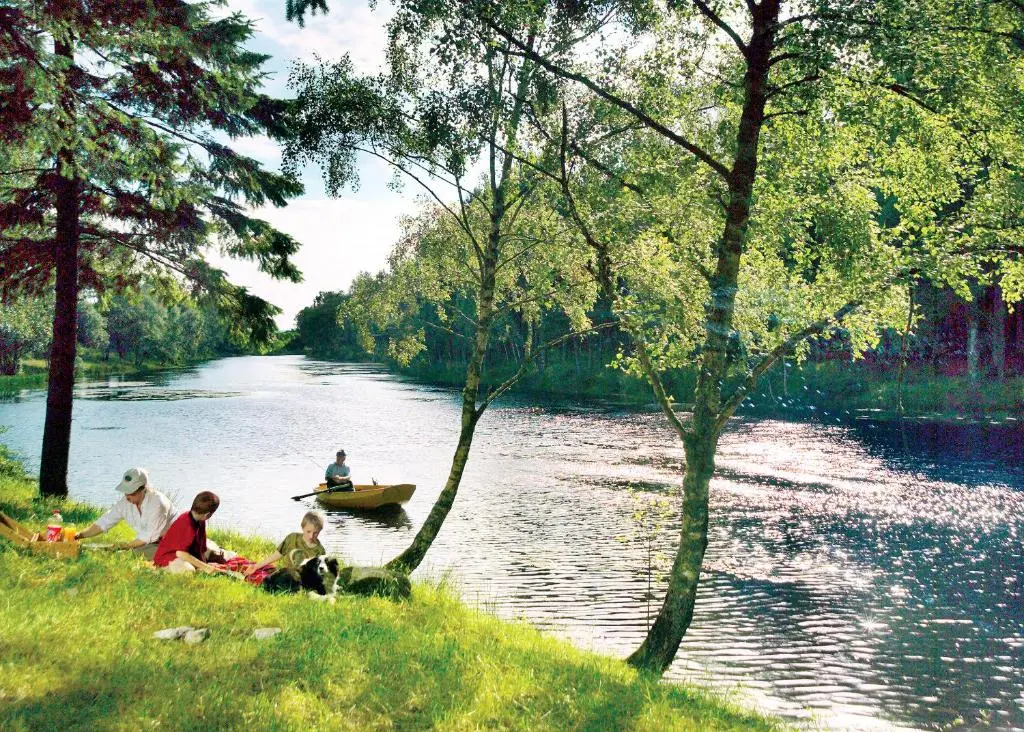 a group of people sitting on the grass next to a river at Delny Highland Lodges in Barbaraville