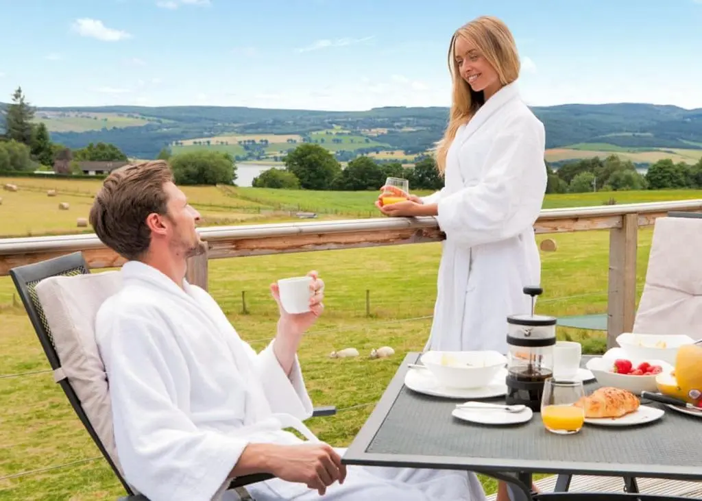 a man and woman sitting at a table with a cup of coffee at Kessock Highland Lodges in Tore