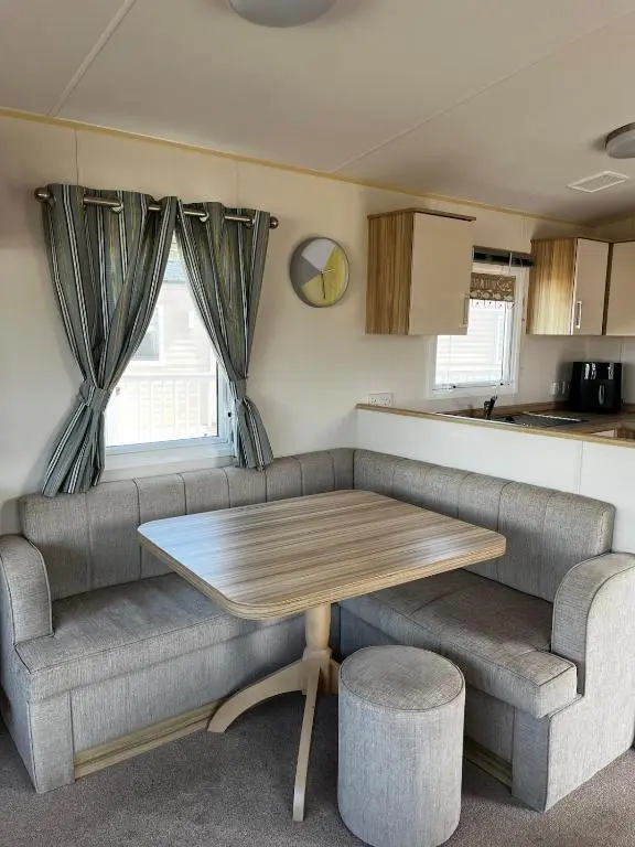 a living room with a table and a couch at Sand Dollar, Silver Sands Holiday Park in Lossiemouth