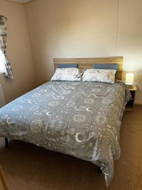 a bedroom with a bed with a comforter and pillows at Sand Dollar, Silver Sands Holiday Park in Lossiemouth