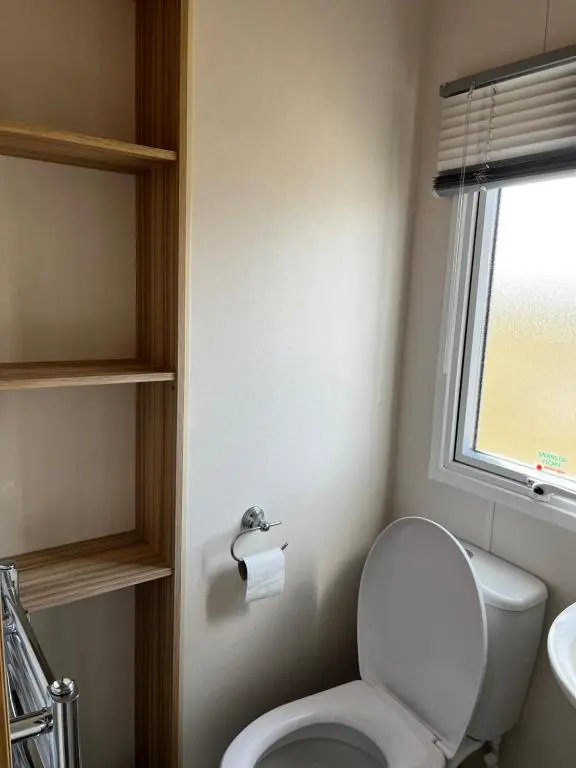 a bathroom with a toilet and a sink and a window at Sand Dollar, Silver Sands Holiday Park in Lossiemouth