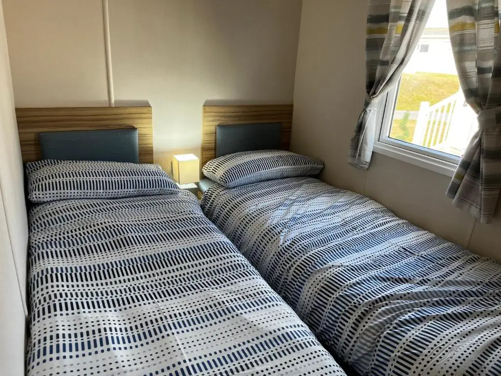 two beds in a small room with a window at Sand Dollar, Silver Sands Holiday Park in Lossiemouth