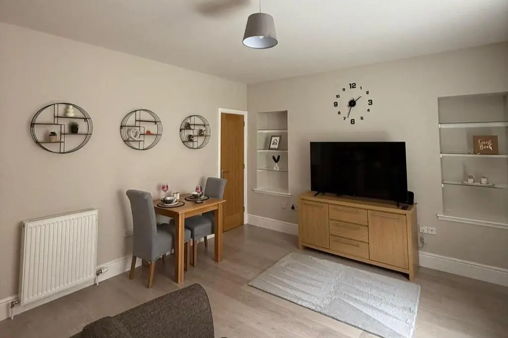 a living room with a television and a table with chairs at 1 Bed Flat - Sleeps 2 - Parking - Wifi in Nairn