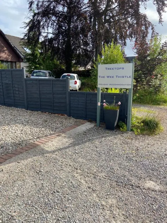a sign in the driveway of a house with a sign at Treetops Bungalow Loch Ness in Drumnadrochit