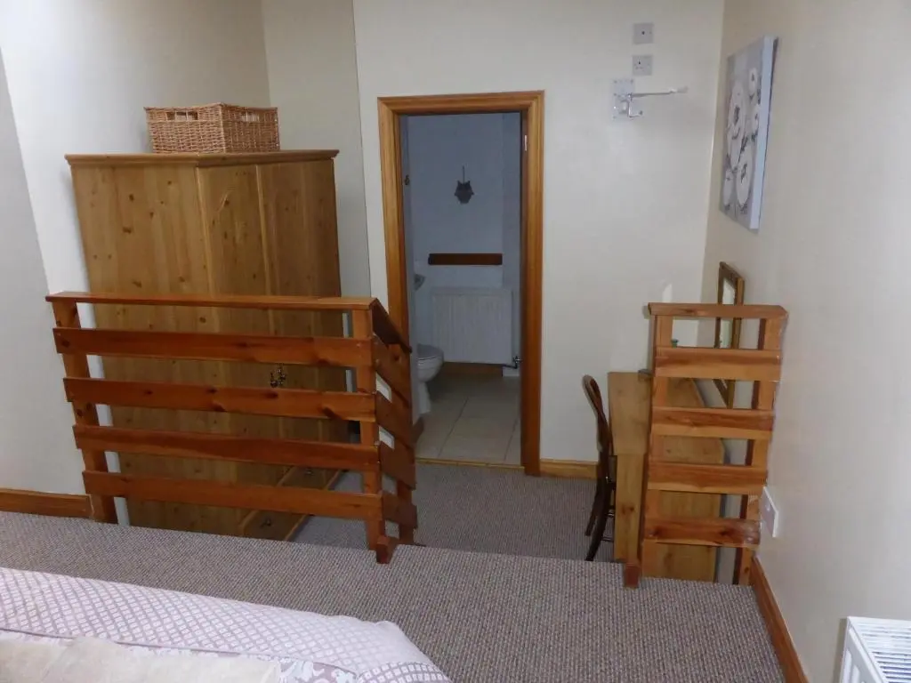 a bedroom with a bed and a staircase and a bathroom at Treetops Bungalow Loch Ness in Drumnadrochit