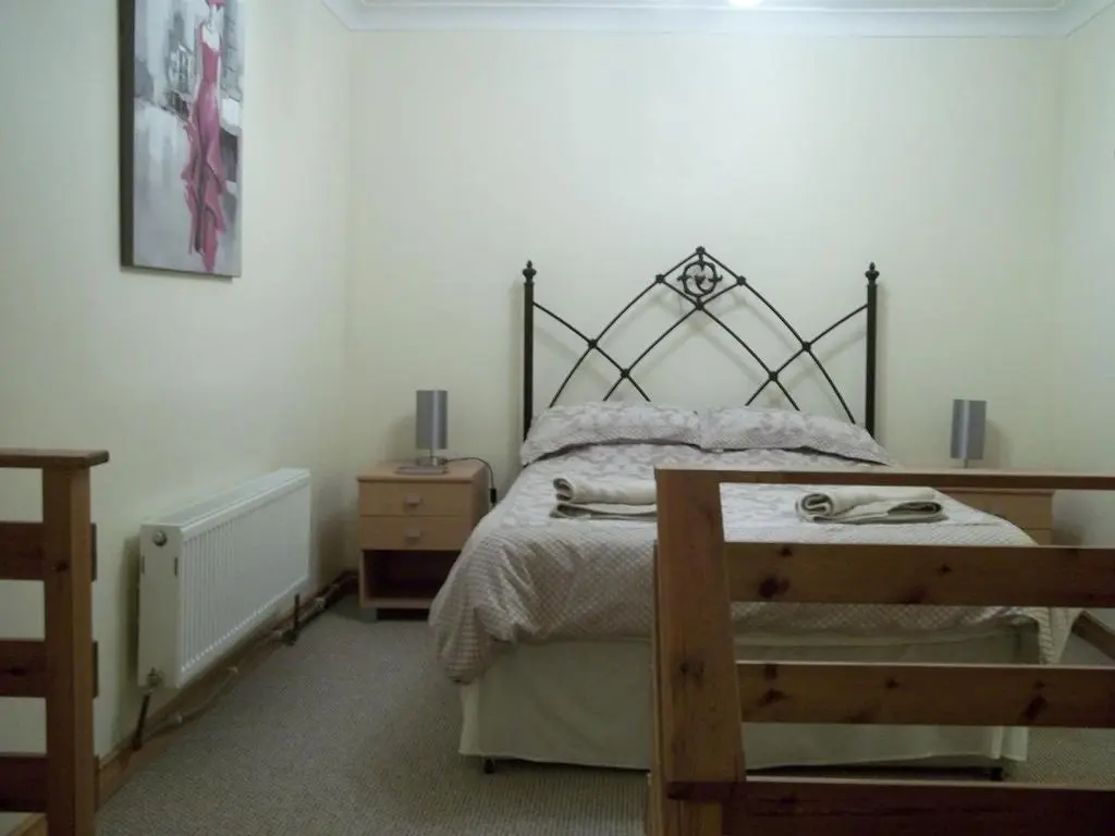 a bedroom with a bed and a night stand and a table at Treetops Bungalow Loch Ness in Drumnadrochit