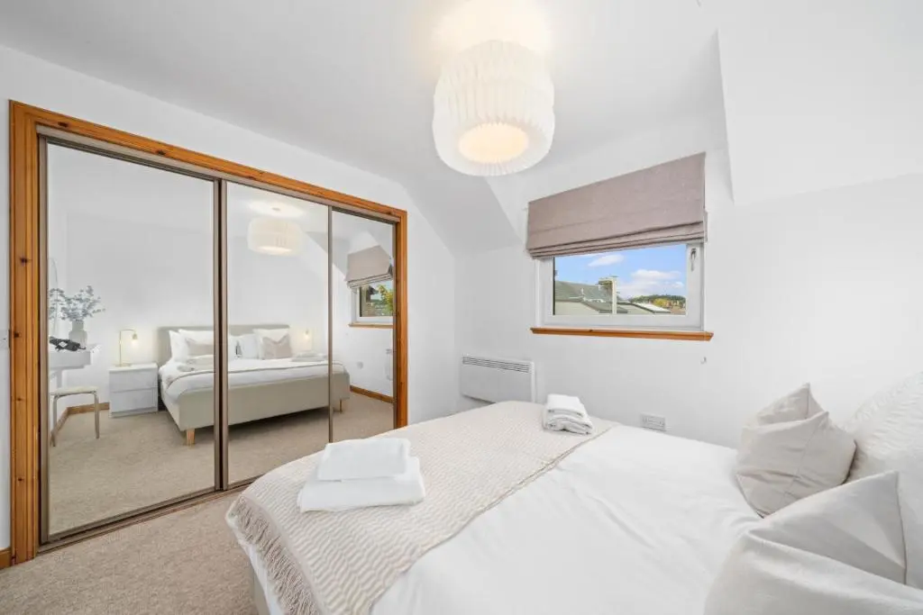a white bedroom with a bed and a mirror at King Cosy 2 Bedroom Apartment - Inverness in Inverness