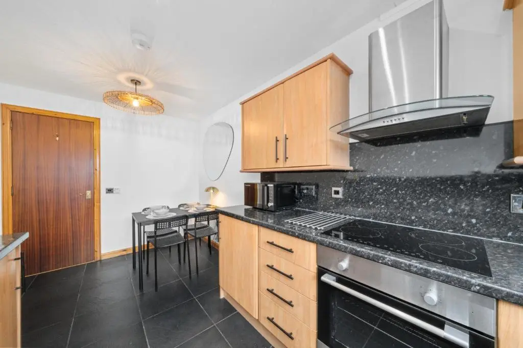 a kitchen with wooden cabinets and a black counter top at King Cosy 2 Bedroom Apartment - Inverness in Inverness