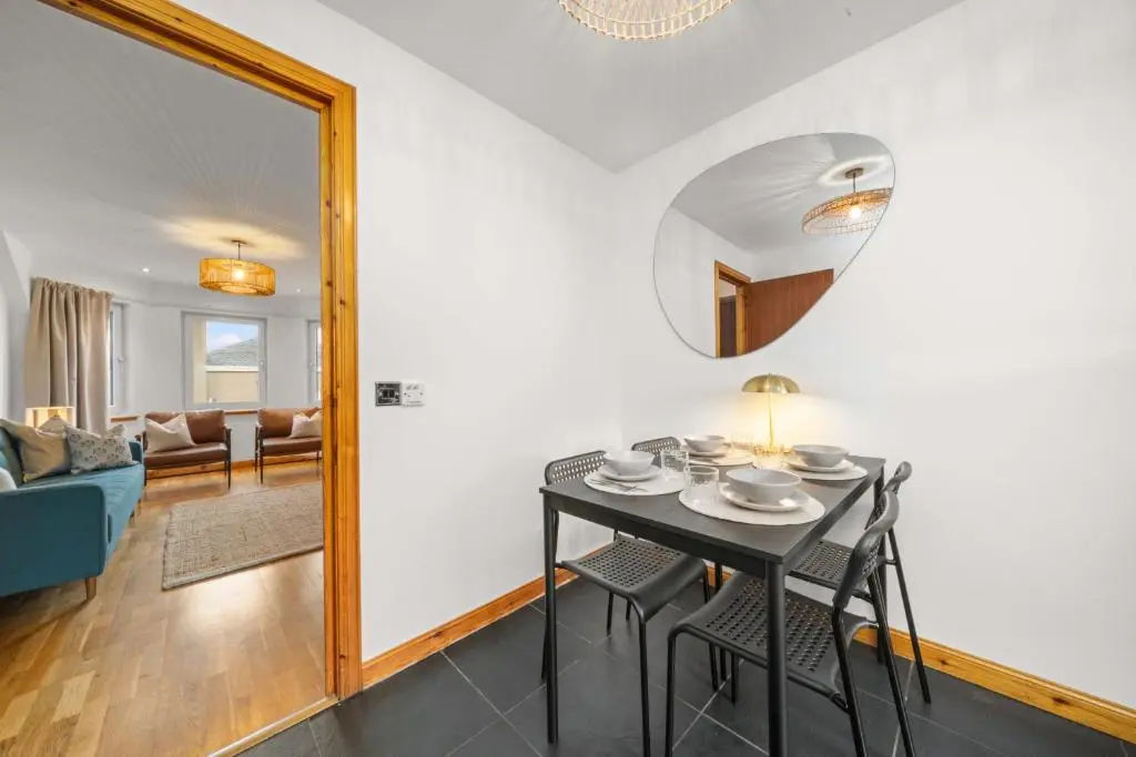 a dining room and living room with a table and a mirror at King Cosy 2 Bedroom Apartment - Inverness in Inverness