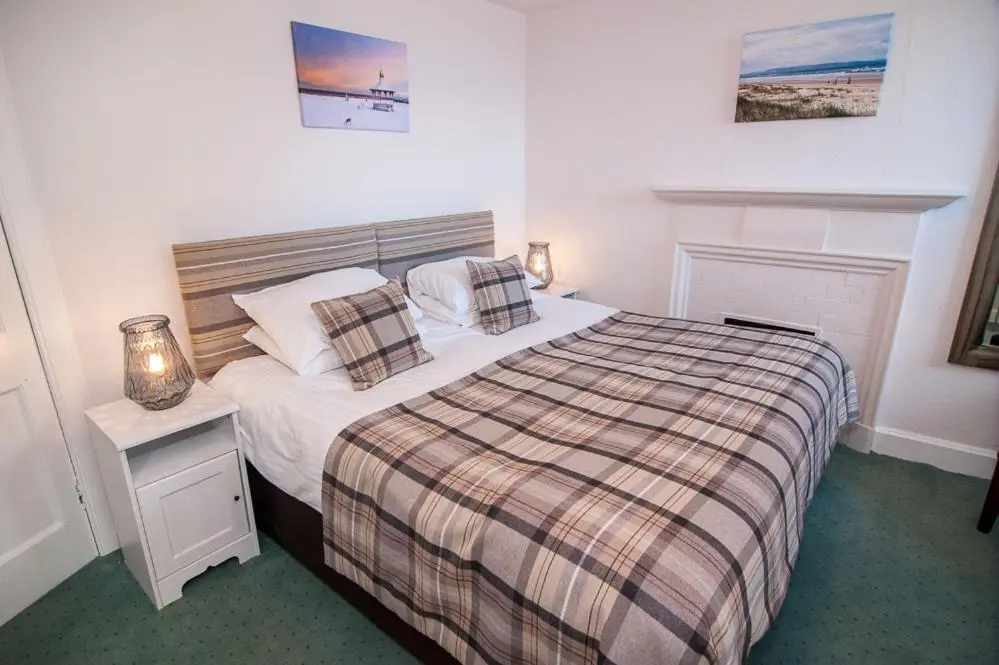 a bedroom with a bed with a plaid blanket and pillows at The Penthouse Self Catering in Nairn