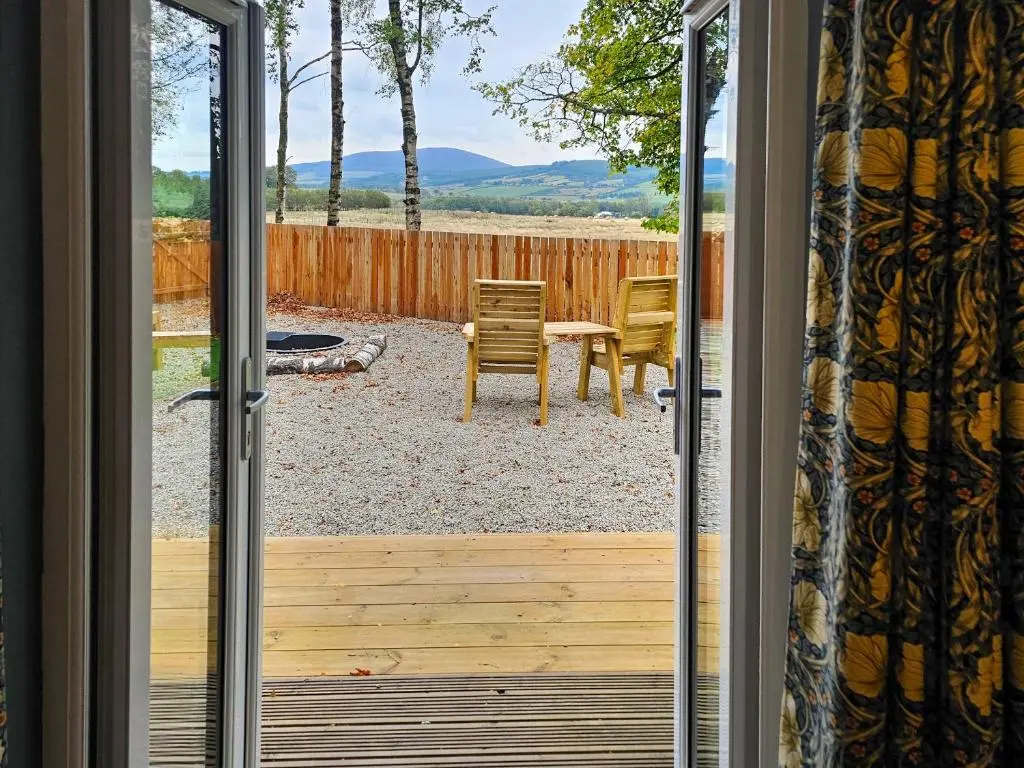 a door open to a patio with a table and chairs at Gallowhill Kirkside - Uk46515 in Newmill