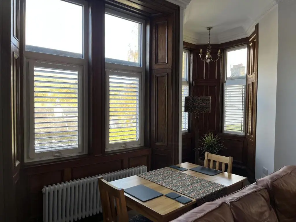 a living room with a table and some windows at Bank House apartment in Fort Augustus
