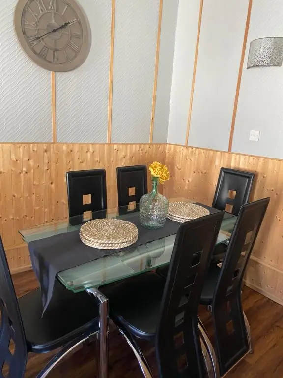a dining room table with chairs and a clock on the wall at Georges holiday apt the blue suite in Inverness