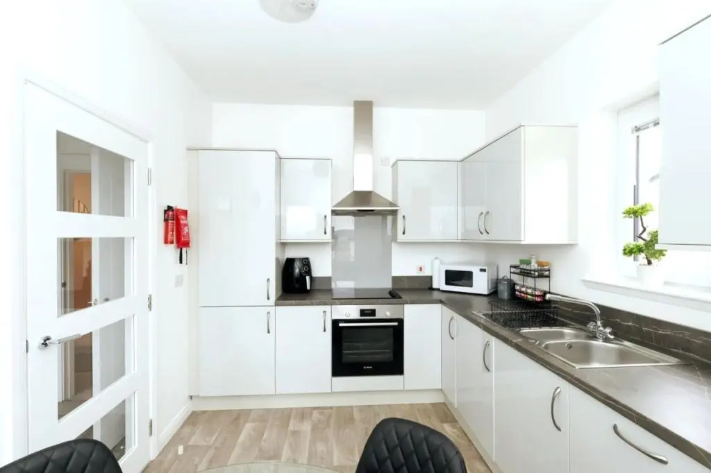 a white kitchen with white cabinets and a sink at Inverness Haven: Bright 2B/2B with Scenic Views in Inverness