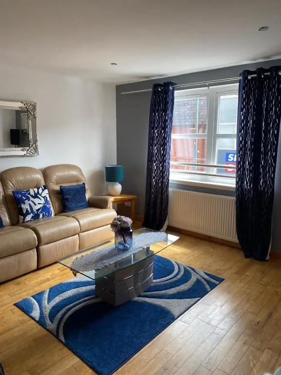 a living room with a couch and a blue rug at Georges 1Faraline court Apartment in Inverness
