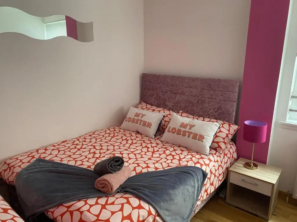 a bedroom with a bed with orange and white sheets at Georges 1Faraline court Apartment in Inverness