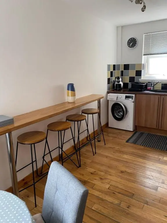 a kitchen with a counter and stools in a room at Georges 1Faraline court Apartment in Inverness