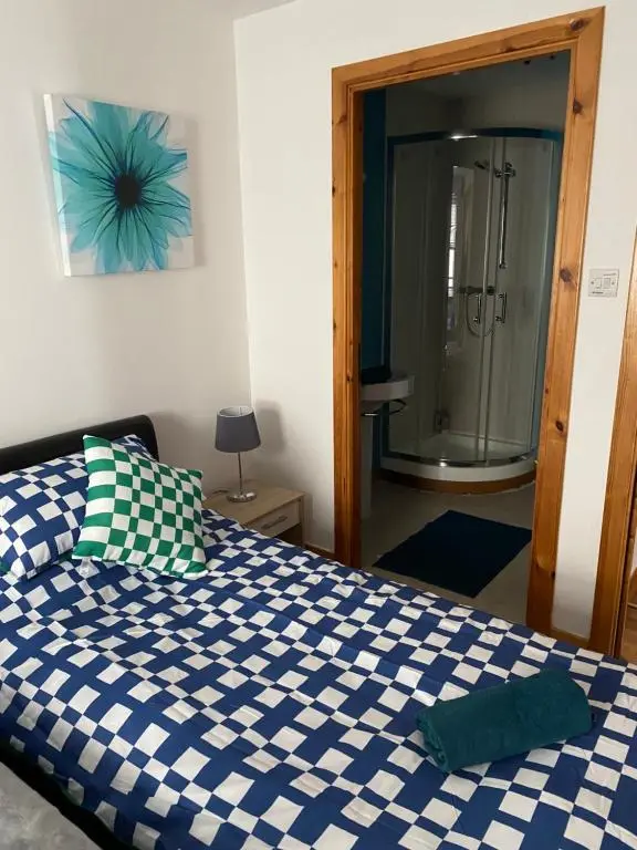a bedroom with a blue and white bed and a shower at Faraline in Inverness