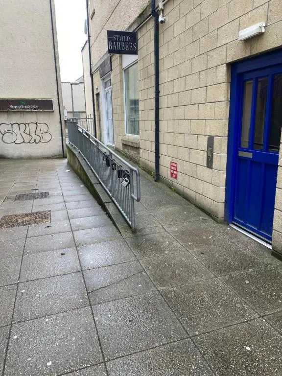 a sidewalk next to a building with a blue door at Faraline in Inverness