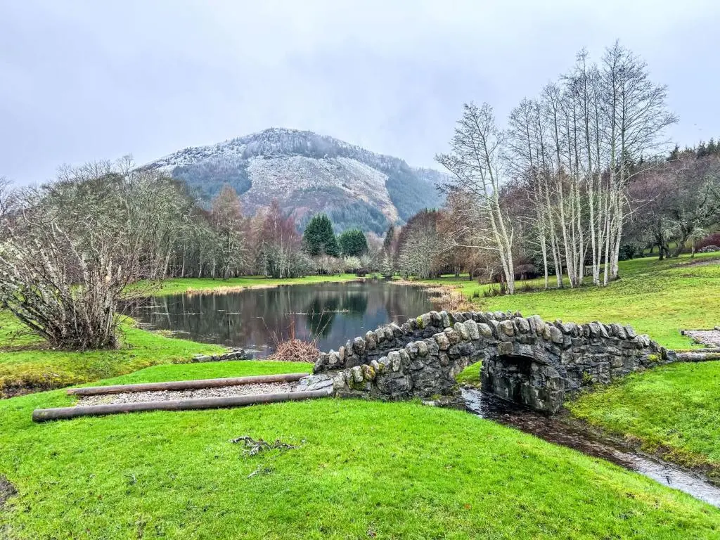 a stone bridge over a river with a mountain in the background at Holiday Home The Romantic Bothy by Interhome in Invermoriston