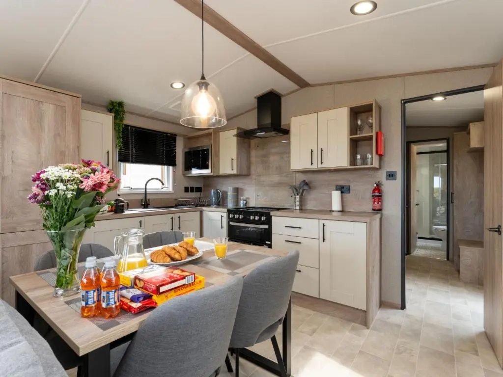 a kitchen with a table with food and flowers on it at Chalet Lodge 15 by Interhome in Boat of Garten