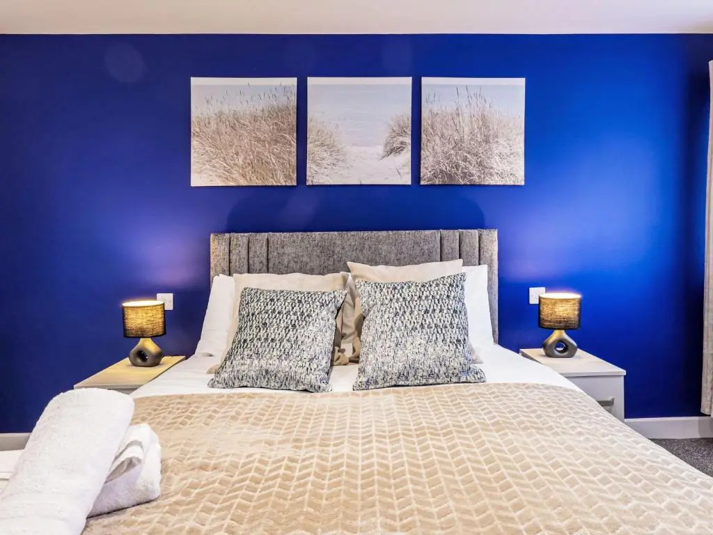 a bedroom with blue walls and a bed with two lamps at Holiday Home Gordonstoun Cottage by Interhome in Elgin