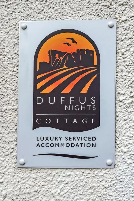 a sign on the side of a building with a sunset at Holiday Home Gordonstoun Cottage by Interhome in Elgin