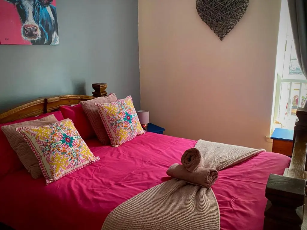 a pink bed with a teddy bear sitting on it at Church st 48B in Inverness